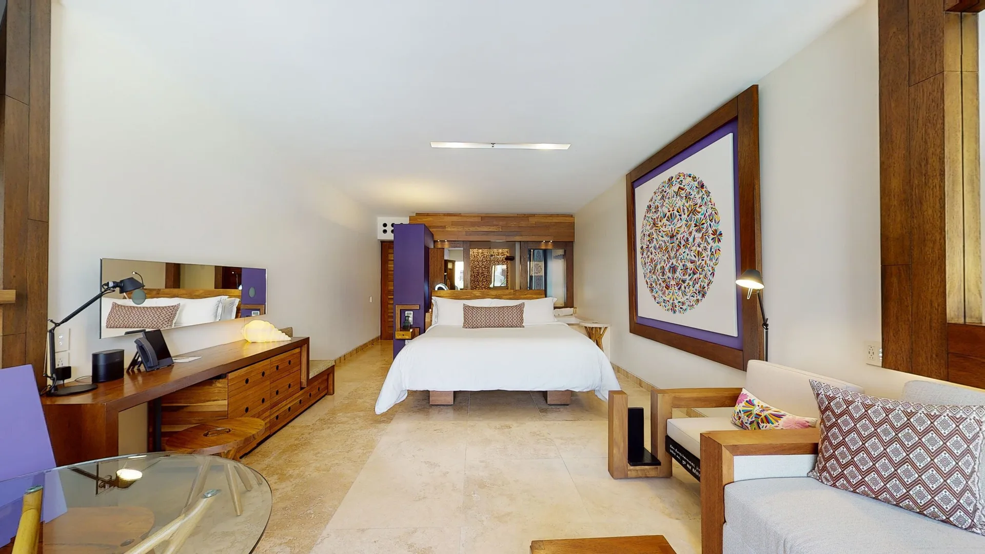 Garden Spa suite bedroom and sitting area at Hotel Xcaret Arte with wood furniture and colorful wall art.