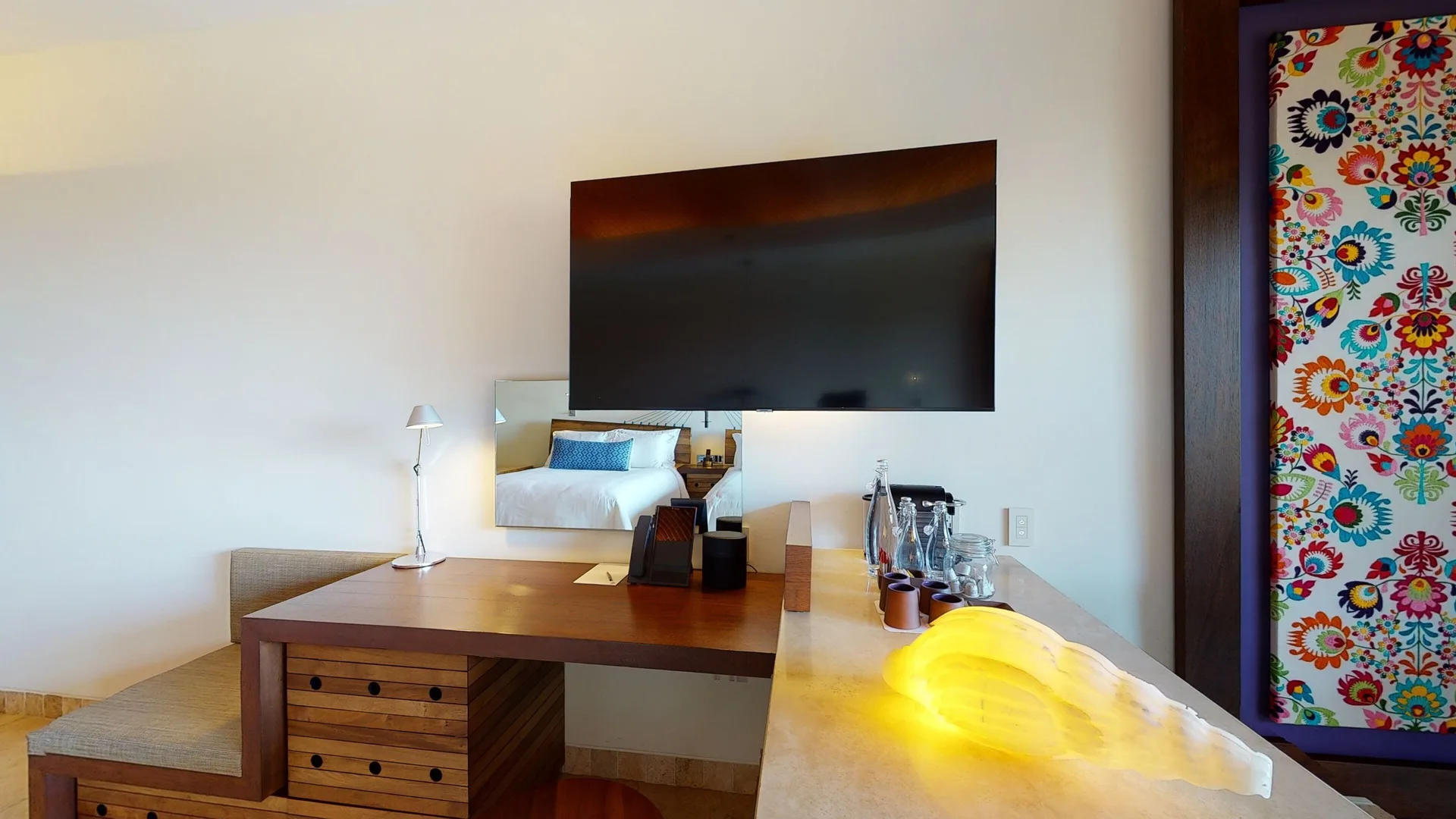 Garden suite desk, TV, minibar area, and colorful wall panel at Hotel Xcaret Arte.