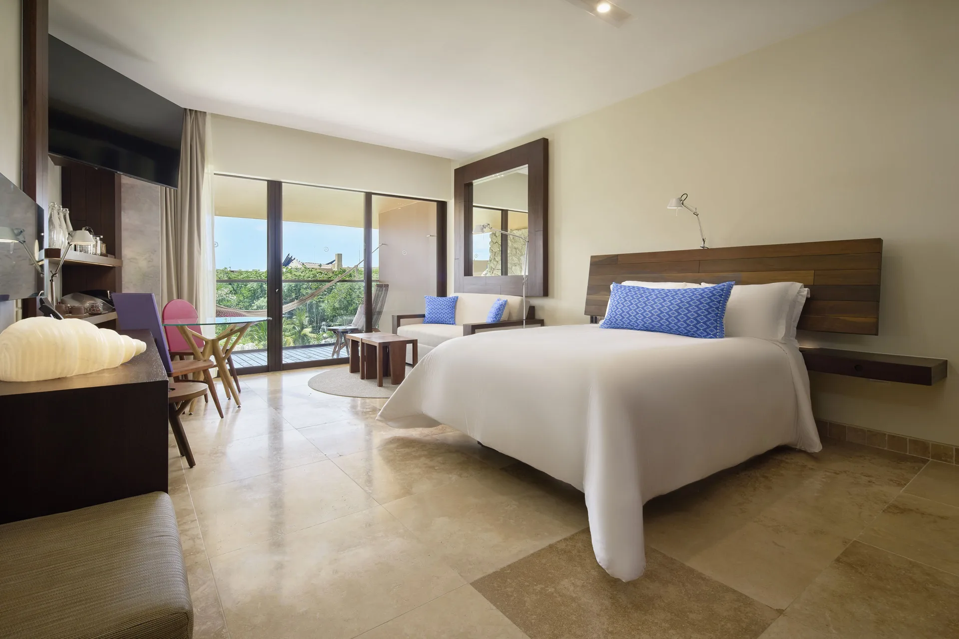 Garden suite with king bed, seating area, balcony, and greenery at Hotel Xcaret Arte.