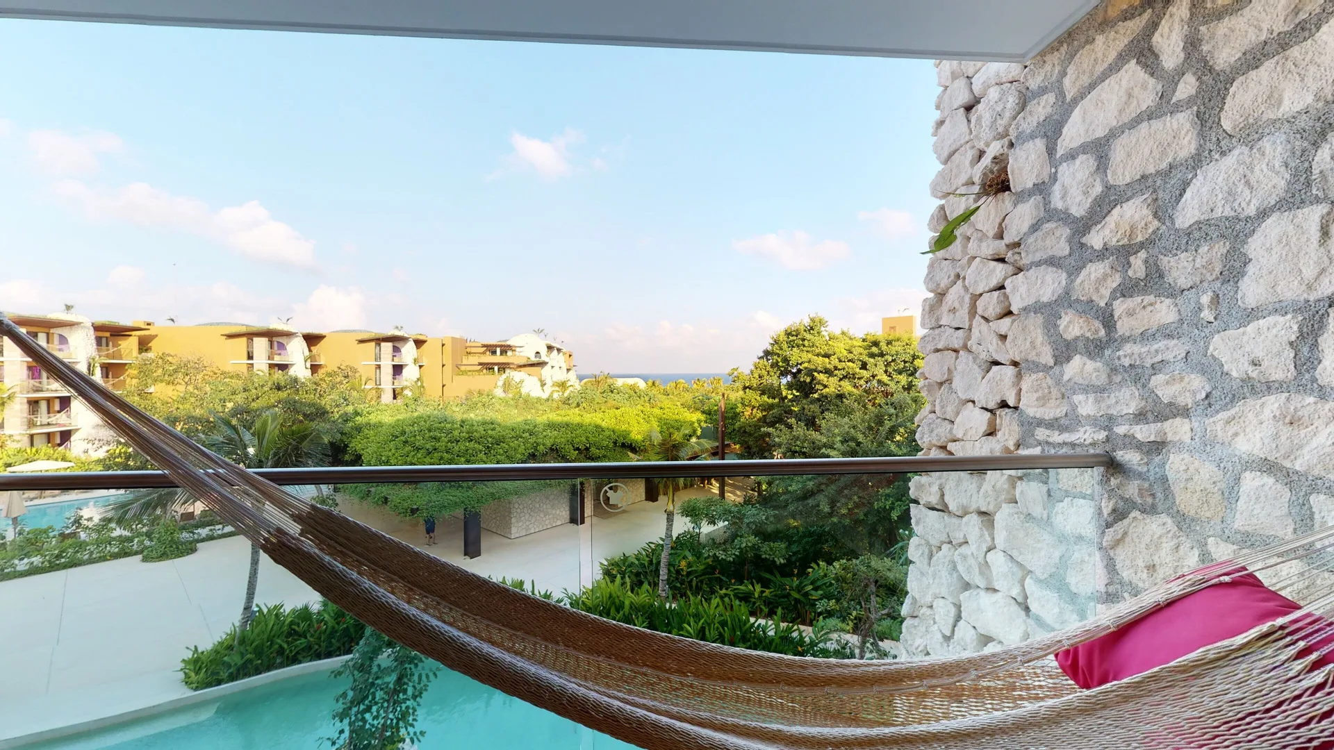Ocean View Suite balcony hammock with greenery and ocean in the distance at Hotel Xcaret Arte.