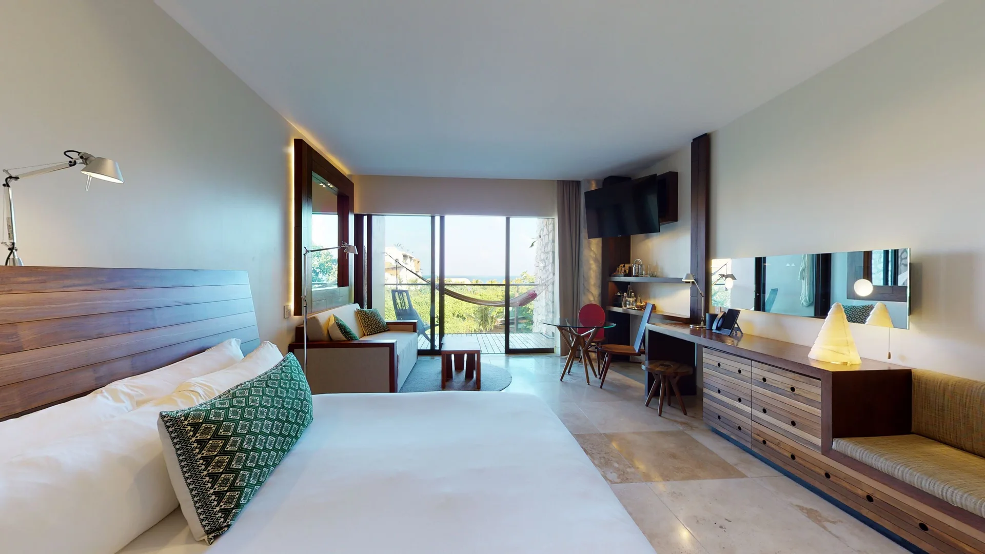 Ocean View Suite with king bed, sofa, desk, and balcony doors at Hotel Xcaret Arte.