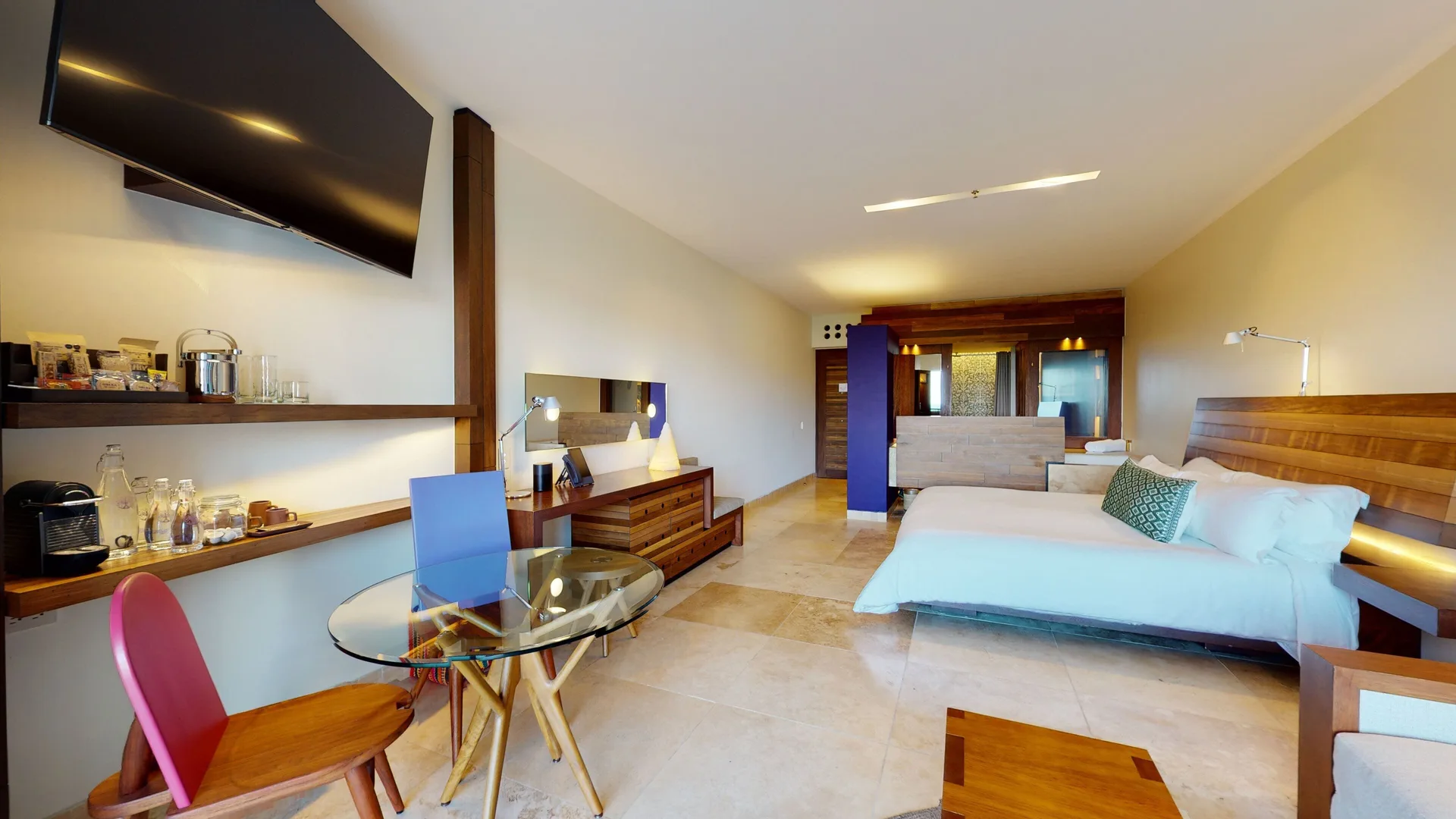 Ocean View Suite with king bed, dining table, television, and refreshment shelves at Hotel Xcaret Arte.