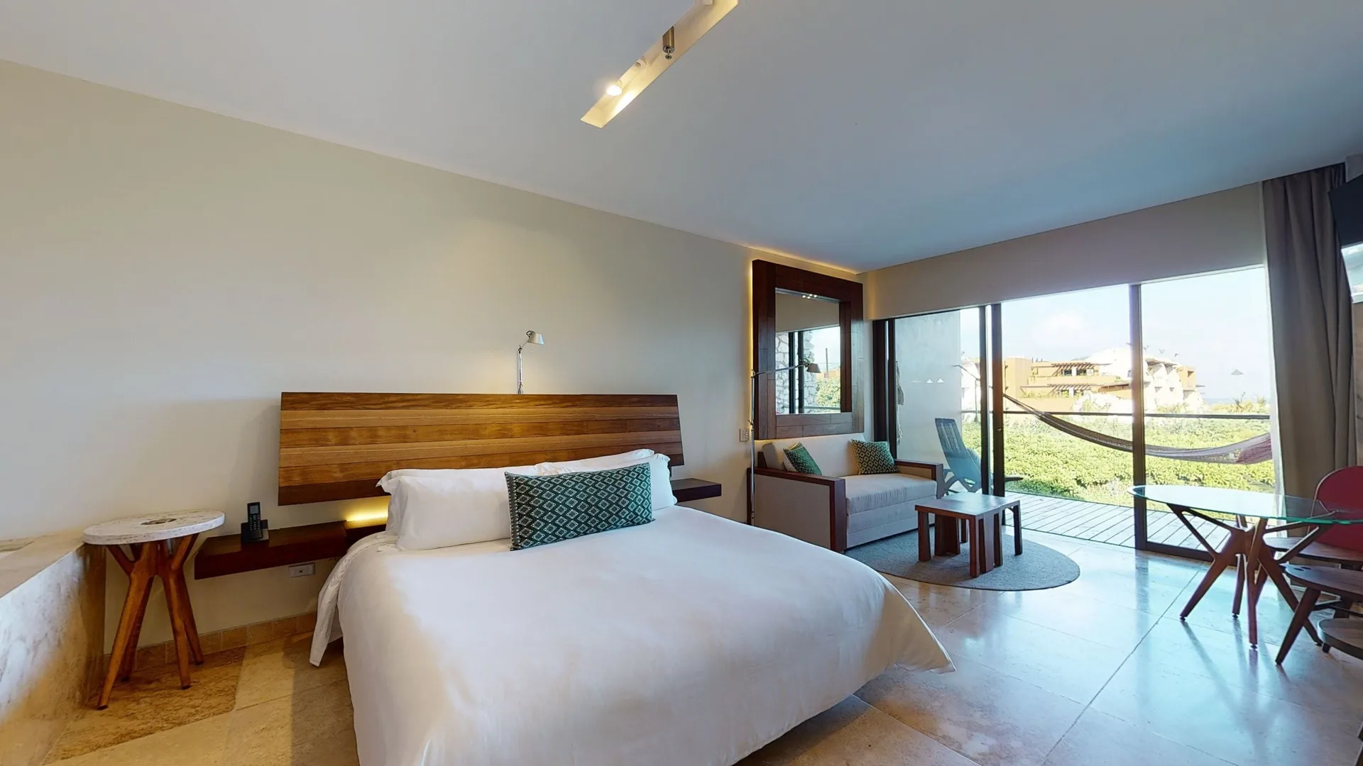 Ocean View Suite king bed beside a sitting area and bright balcony at Hotel Xcaret Arte.