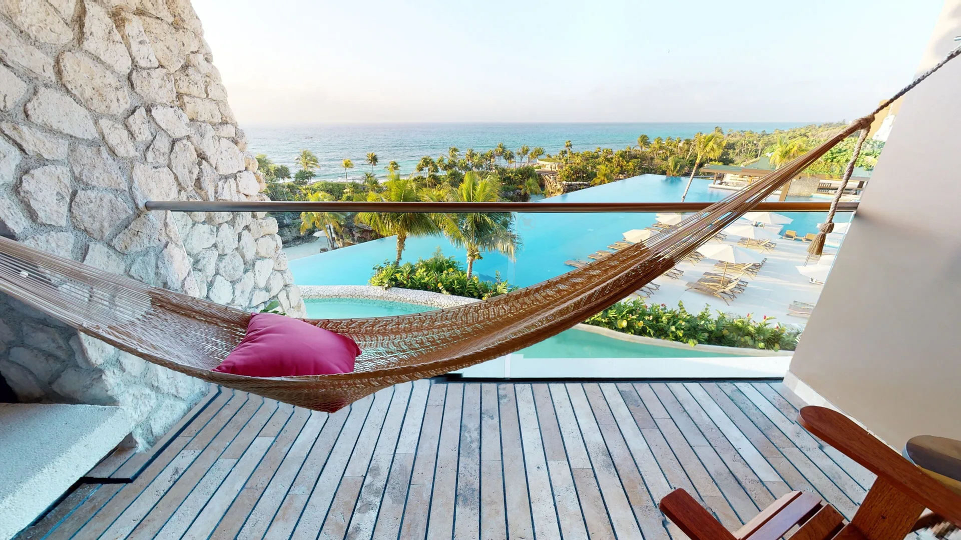 Oceanfront suite balcony hammock with pool, palms, and sea view at Hotel Xcaret Arte.