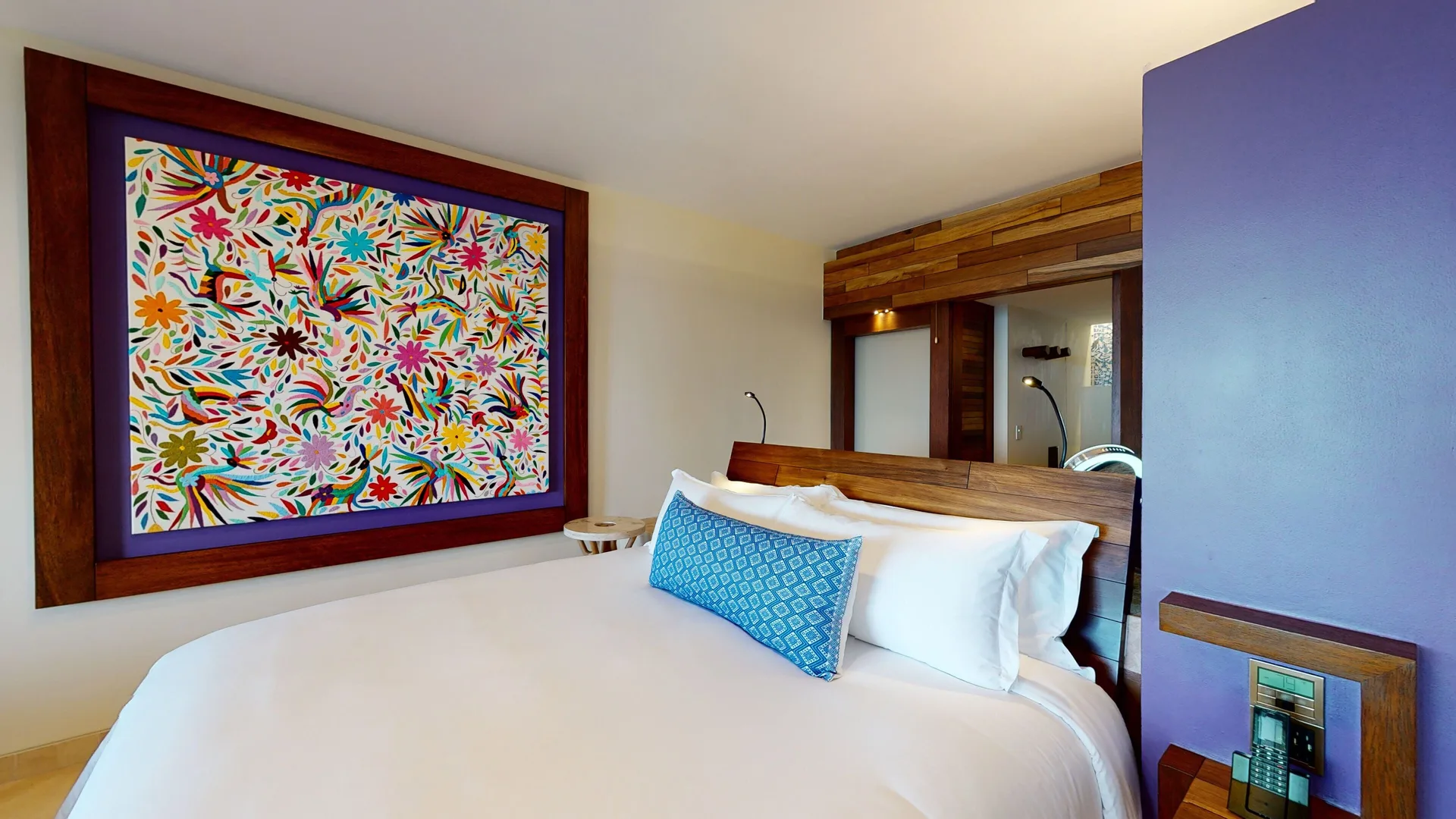 Oceanfront suite king bed with colorful wall art at Hotel Xcaret Arte.