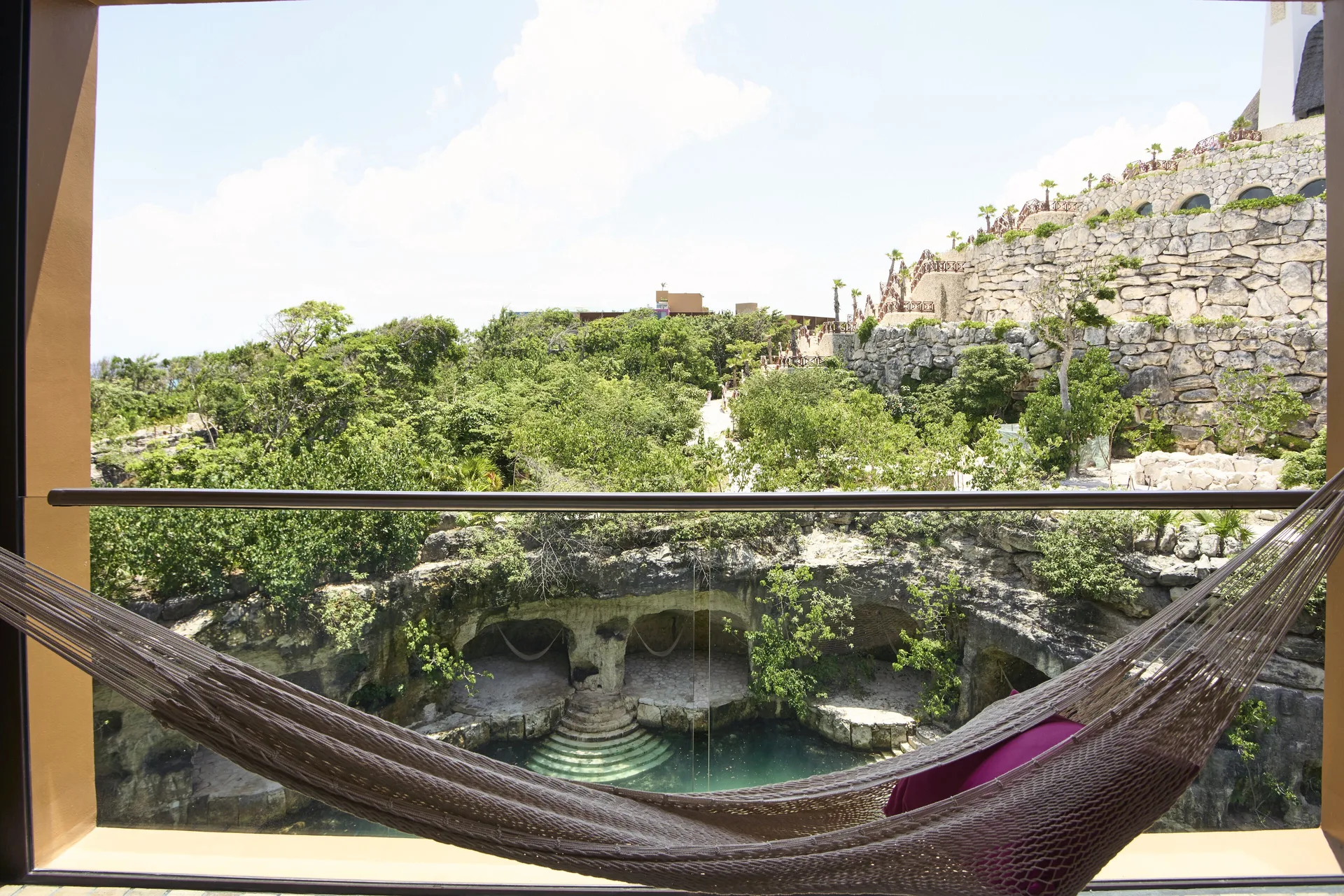 Suite river balcony hammock overlooking water and rocky gardens at Hotel Xcaret Arte.