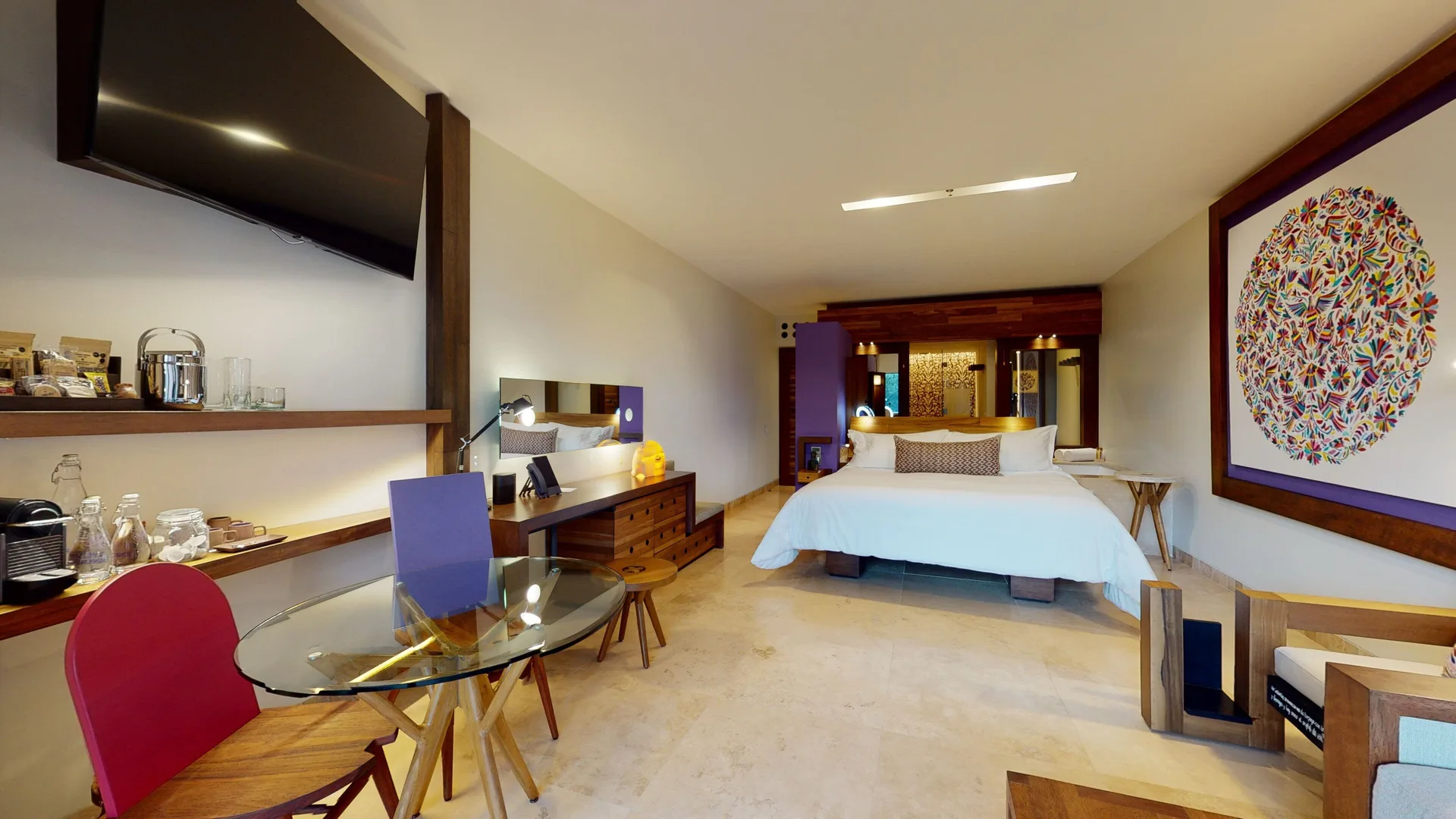 Suite River Spa king bed, dining table, TV and minibar at Hotel Xcaret Arte.