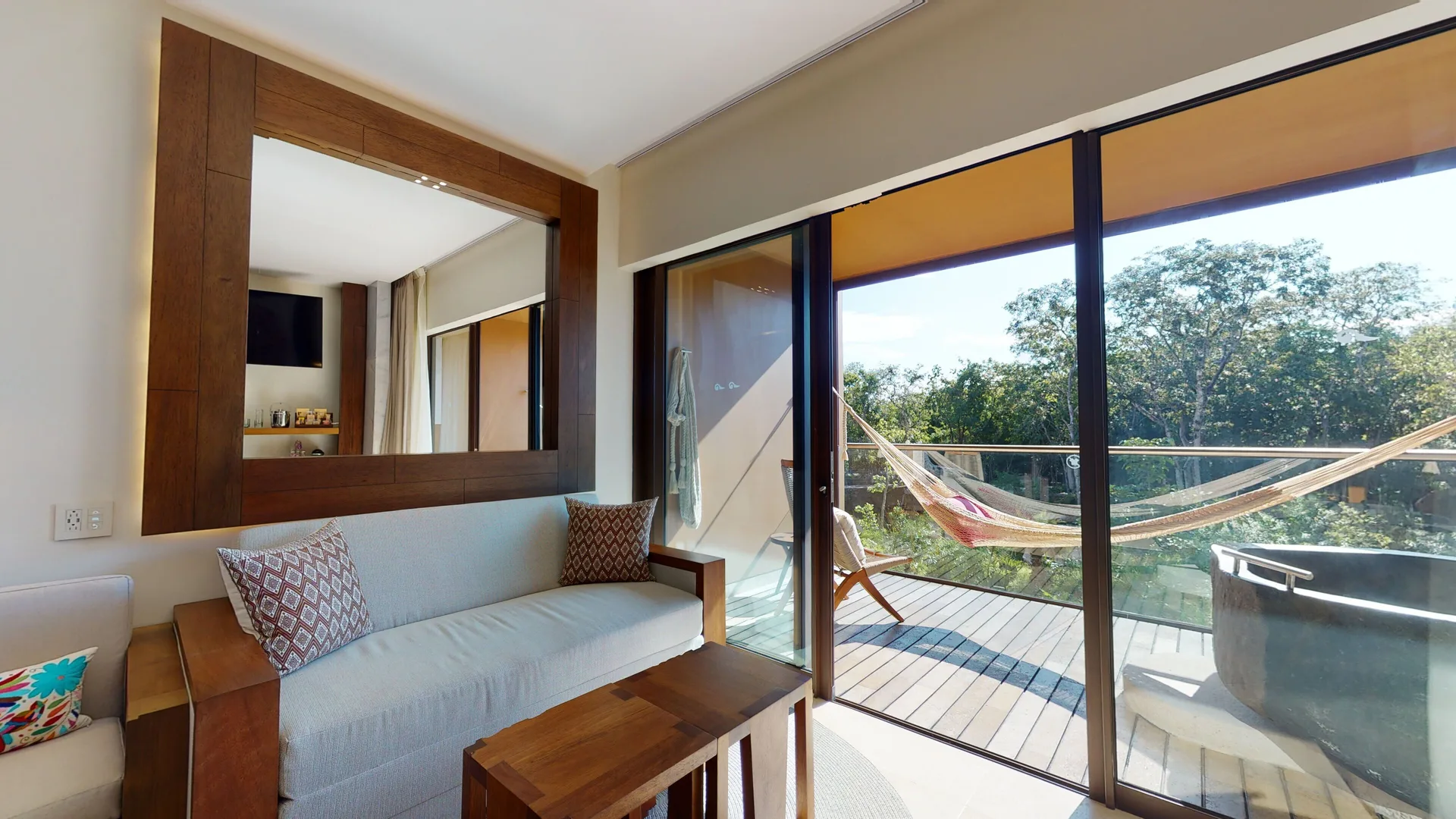 Suite River Spa sofa by balcony with hammock and outdoor tub at Hotel Xcaret Arte.