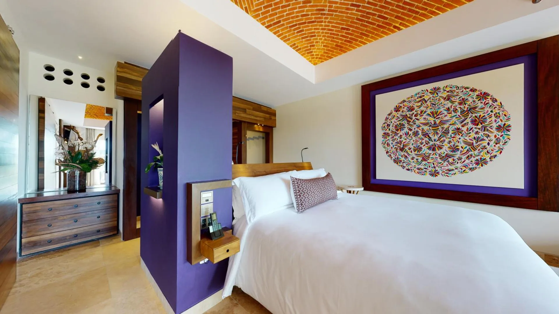 Suite River View bedroom with white bed, purple accent wall, and framed art at Hotel Xcaret Arte.