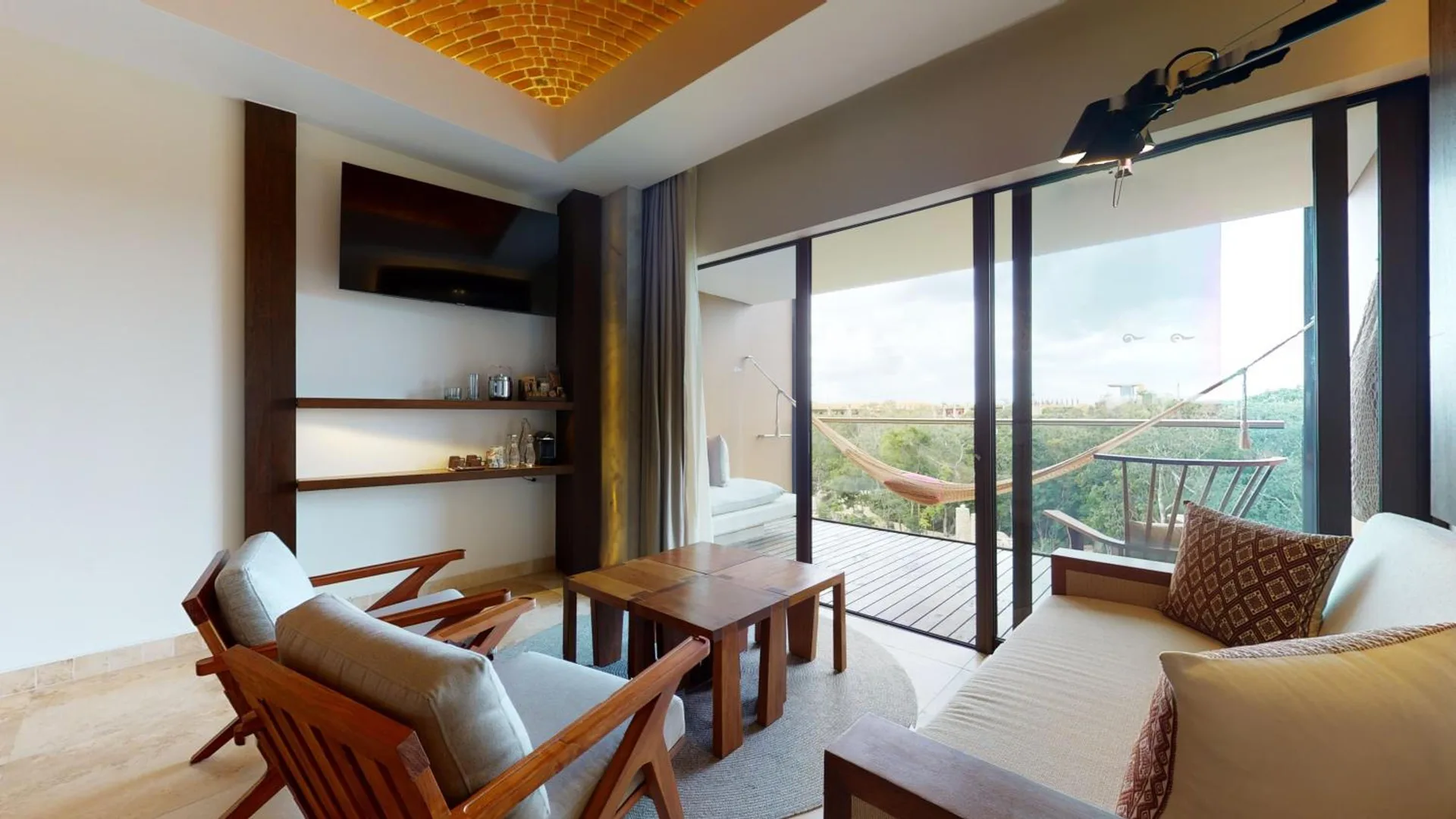 River View suite lounge with balcony hammock and sliding glass doors at Hotel Xcaret Arte.