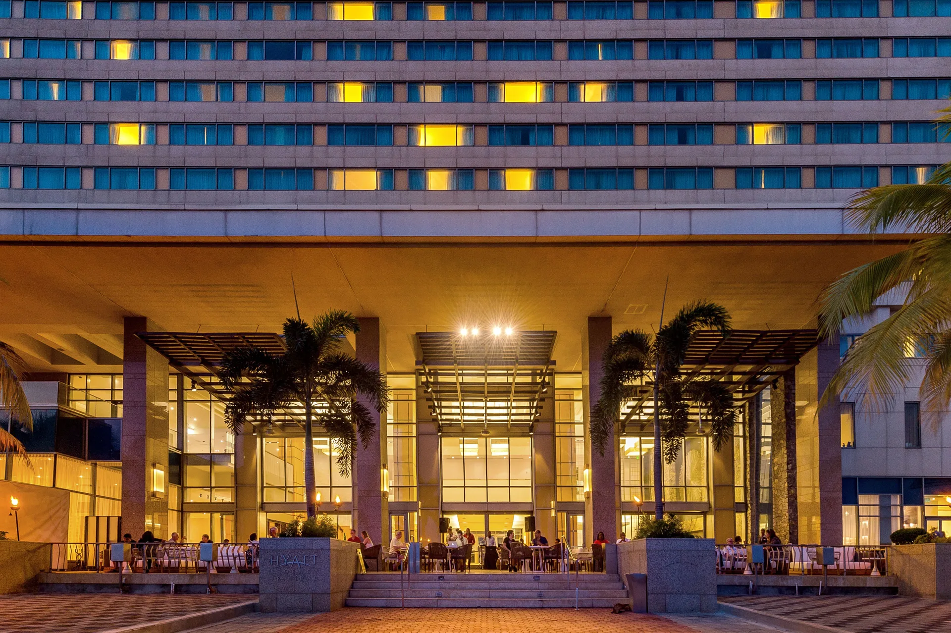 Evening exterior with lit windows and terrace seating at Hyatt Regency Trinidad.