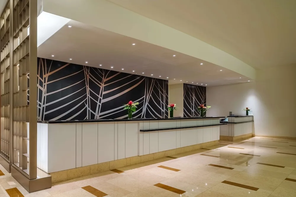 Long front desk at Hyatt Regency Trinidad with flowers and a patterned feature wall.