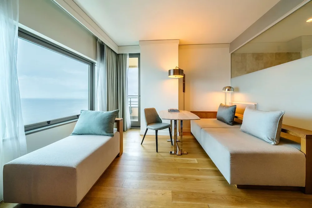 Chaise lounges, table and ocean-facing window in a guest room at Hyatt Regency Trinidad.