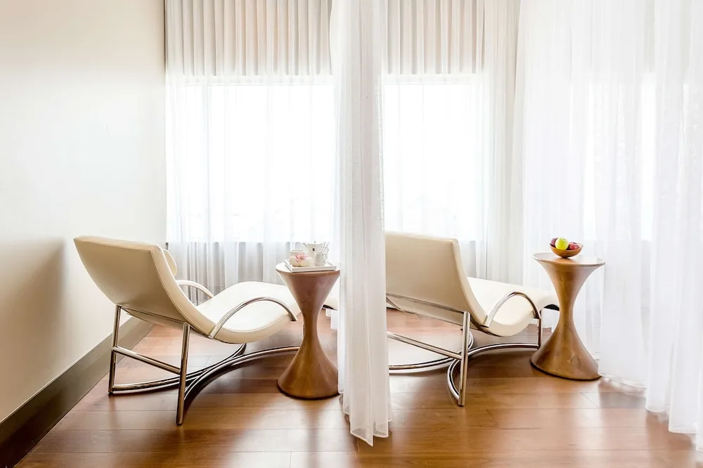 Two spa lounge chairs by sheer-curtained windows at Hyatt Regency Trinidad.