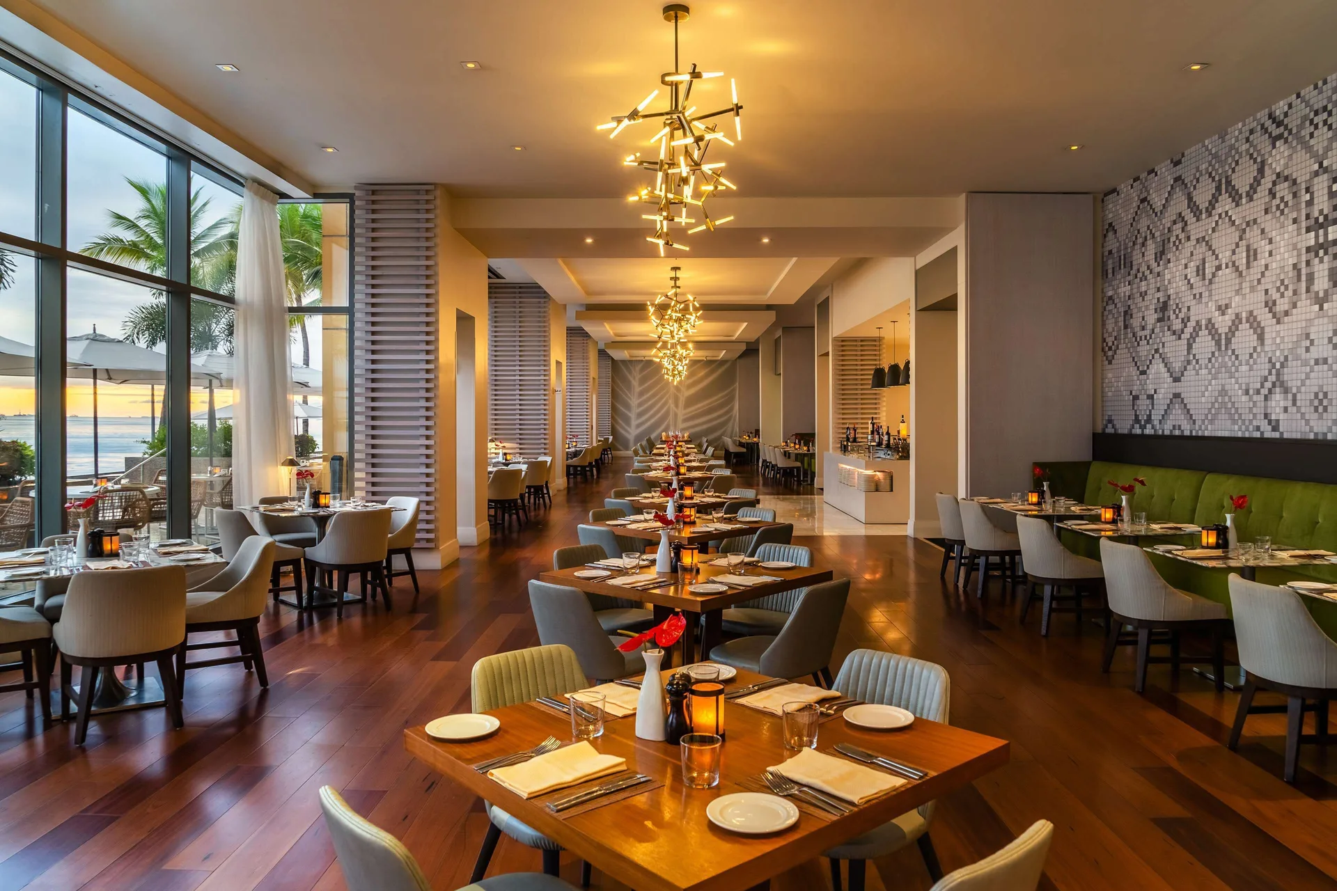 Waterfront dining room with set tables, tall windows, and palm views at Hyatt Regency Trinidad.