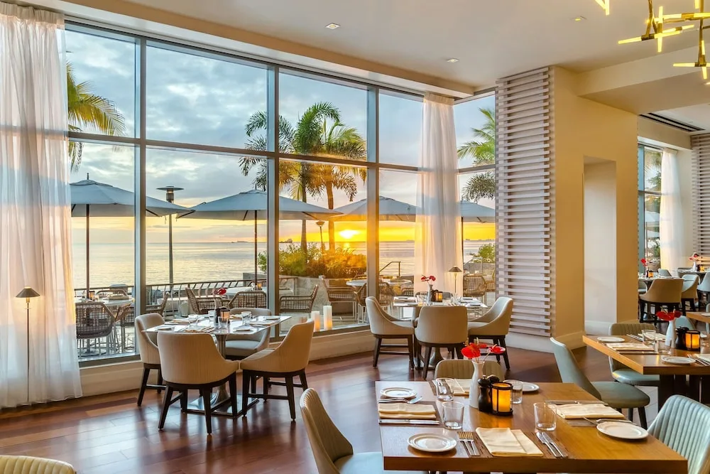 Restaurant tables beside floor-to-ceiling windows at sunset at Hyatt Regency Trinidad.