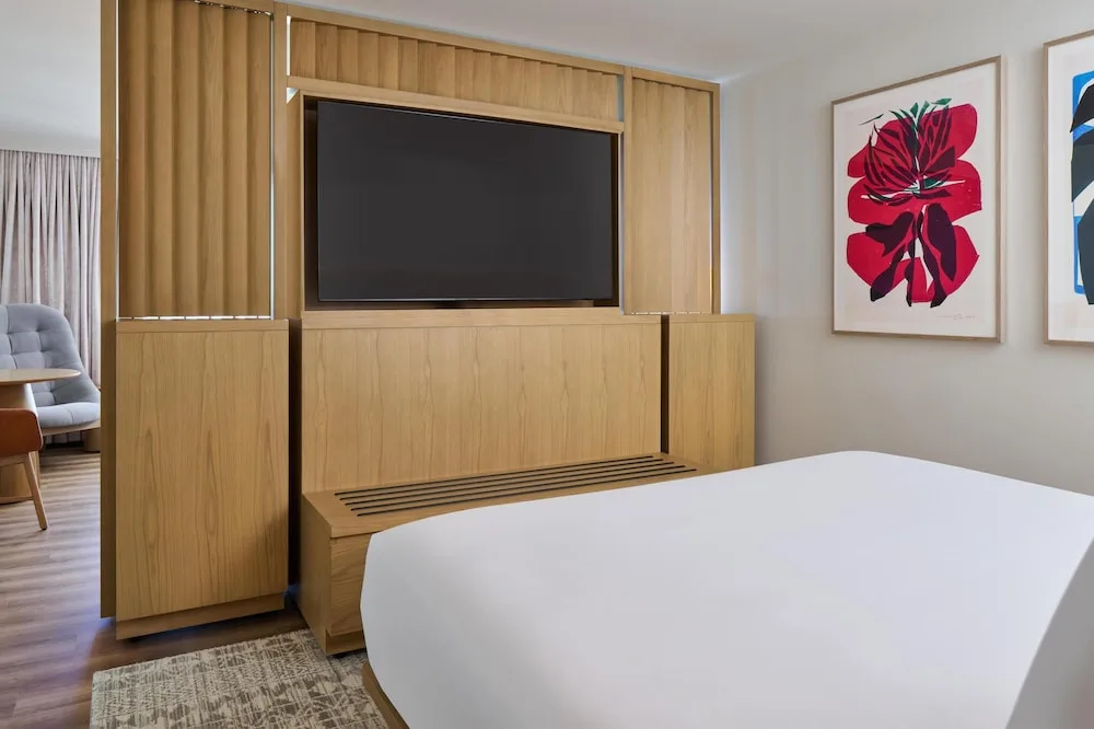 Guest room king bed facing a wood media wall at Hyatt Regency Waikiki Beach Resort & Spa.