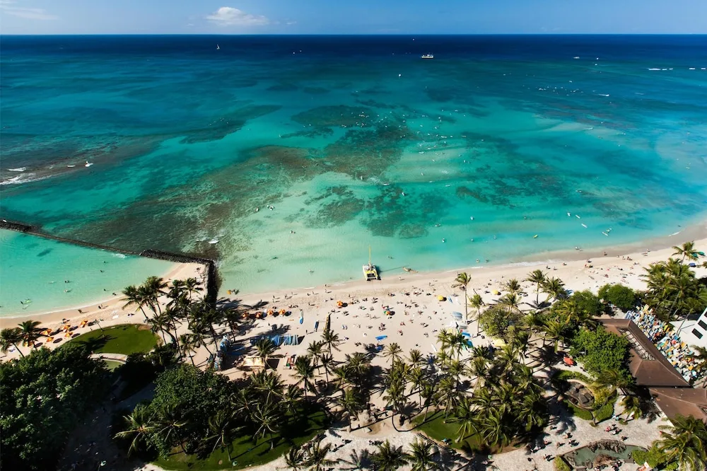 Waikiki Beach and turquoise reef waters sit below Hyatt Regency Waikiki Beach Resort & Spa.