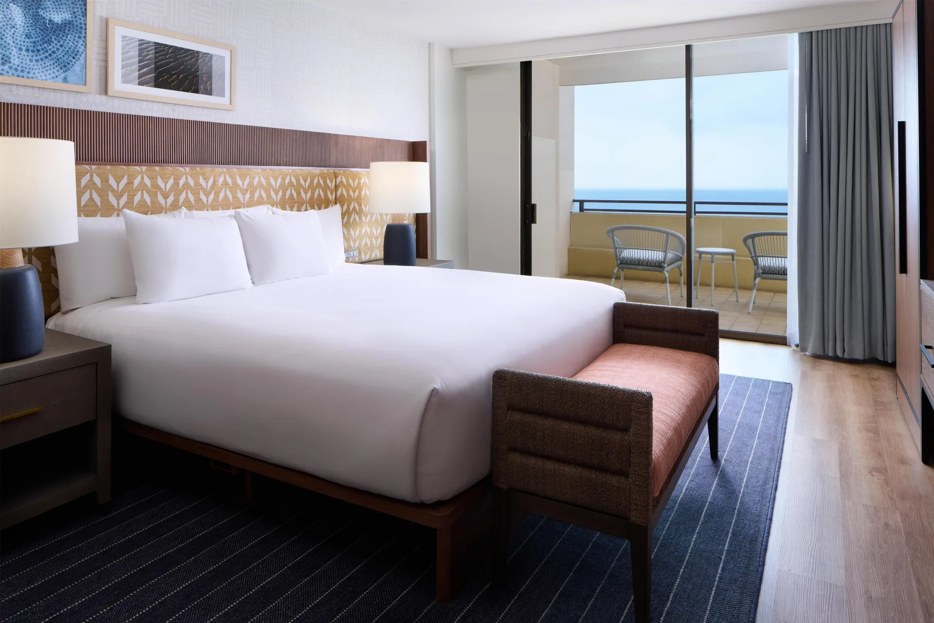 King bed and ocean-view balcony in a deluxe suite at Hyatt Regency Waikiki Beach Resort & Spa.