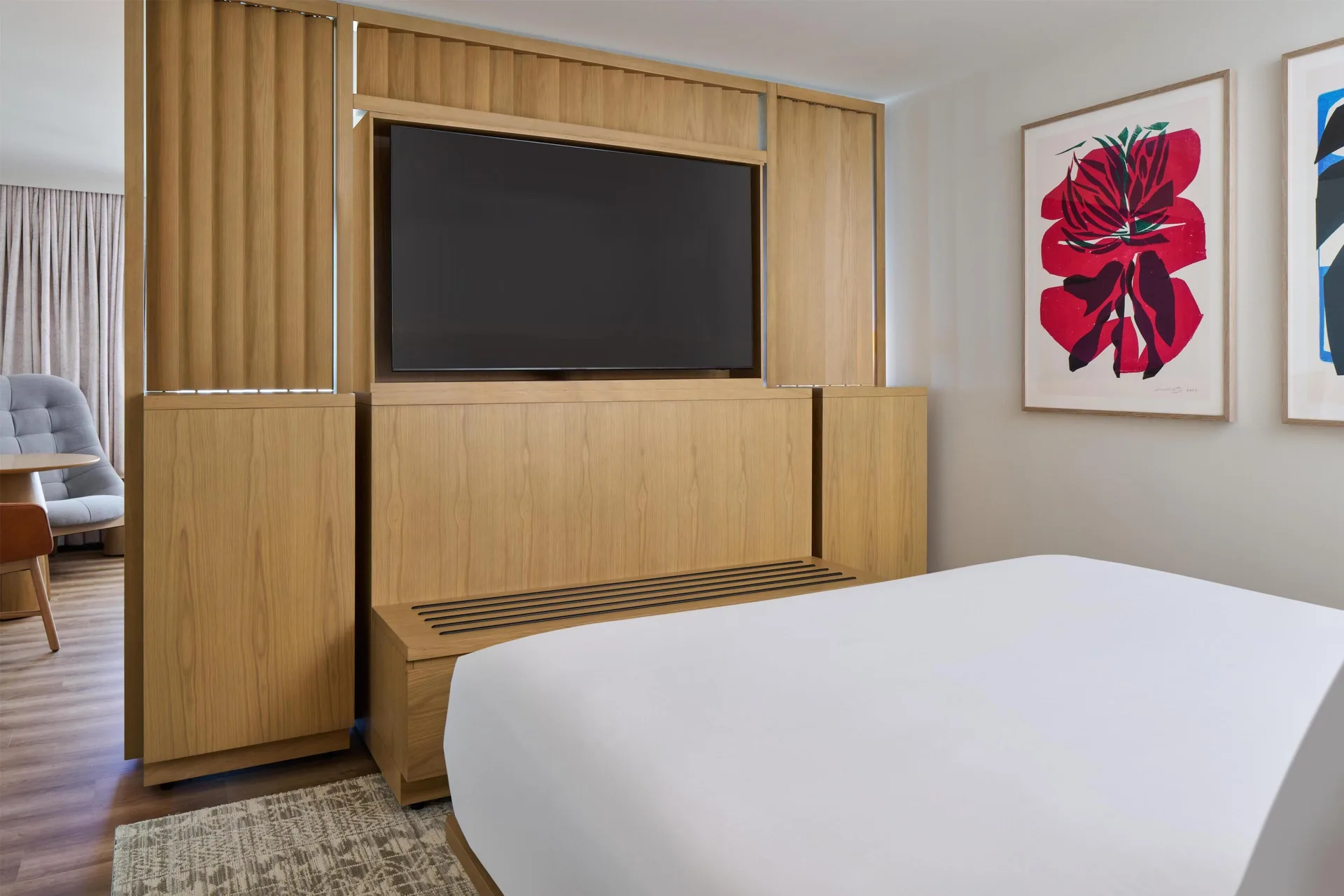Junior Suite bedroom TV wall at Hyatt Regency Waikiki Beach Resort & Spa with artwork and bed edge.