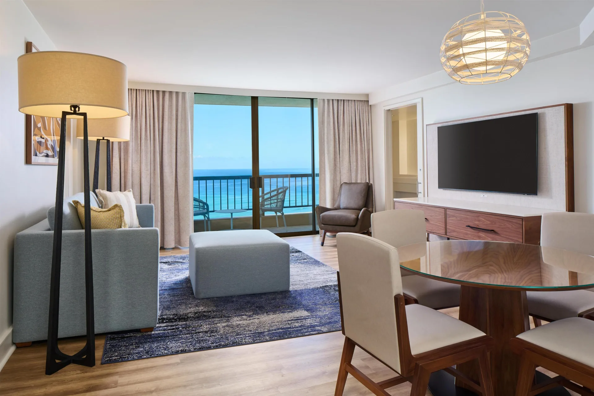 Living and dining area with ocean-facing balcony in a suite at Hyatt Regency Waikiki Beach Resort & Spa.