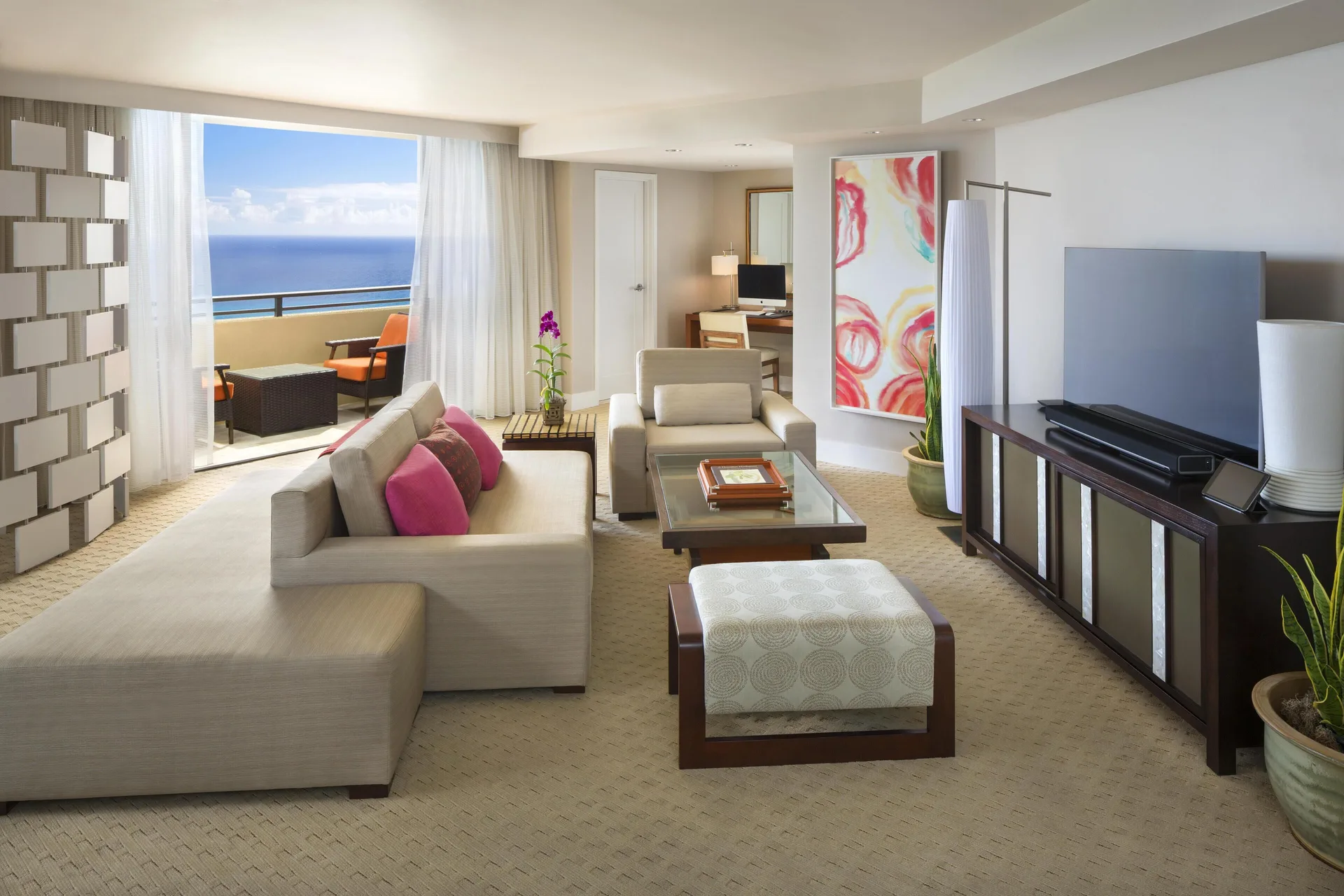 Penthouse suite lounge with sectional sofa, TV, and ocean-view balcony at Hyatt Regency Waikiki Beach Resort & Spa.