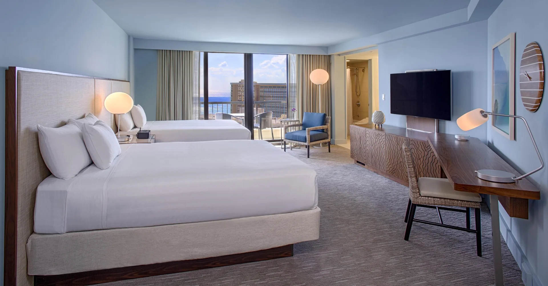 Two bed Ocean View room at Hyatt Regency Waikiki Beach Resort & Spa with TV, desk and shower area.