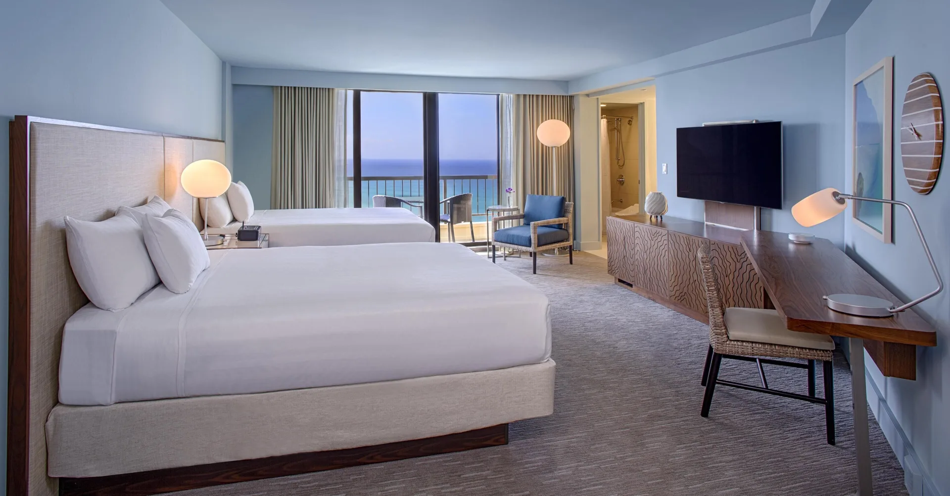 Two-bed oceanfront room with desk and lounge chair at Hyatt Regency Waikiki Beach Resort & Spa.