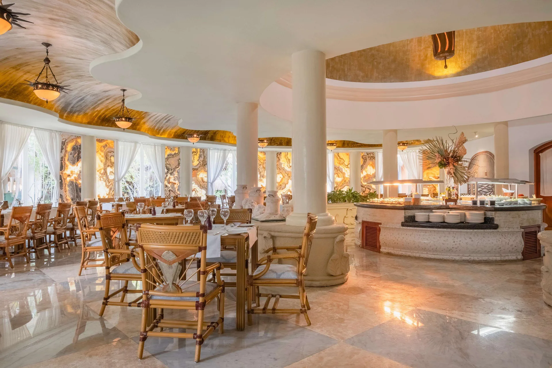 Bright buffet dining room with white columns and woven chairs at Iberostar Waves Paraíso del Mar.