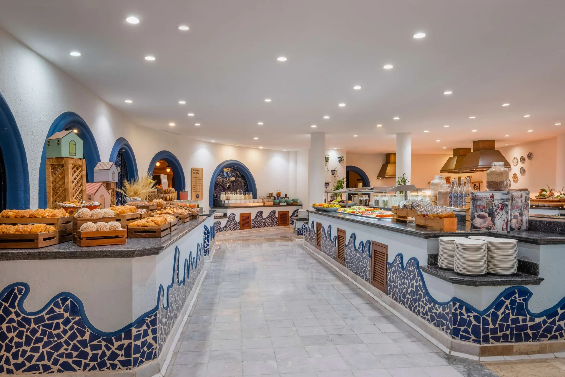 Buffet counter with breads, plates, and blue mosaic tile at Iberostar Waves Paraíso del Mar.