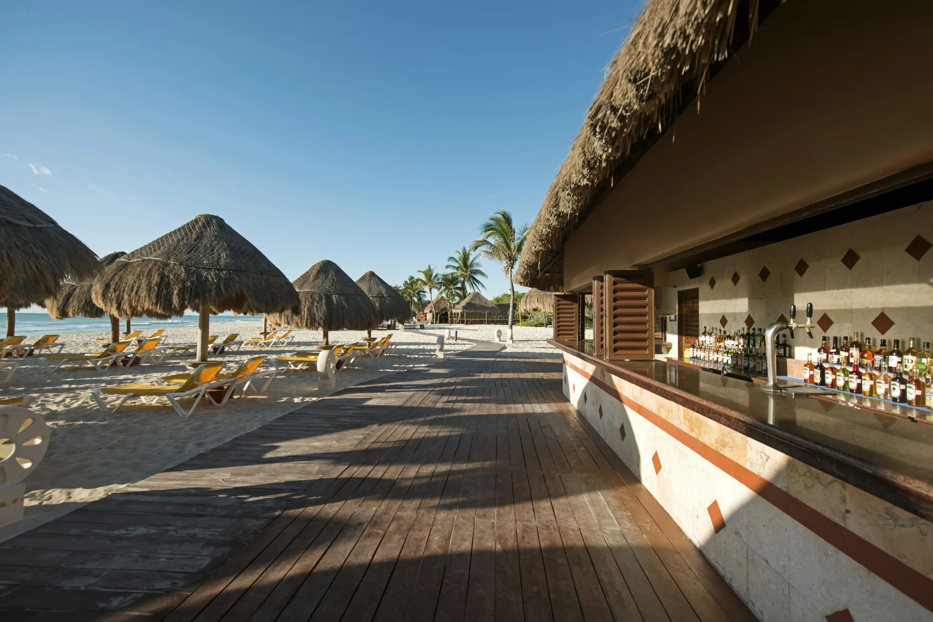 Beach bar beside palapas and lounge chairs at Iberostar Waves Paraíso del Mar.