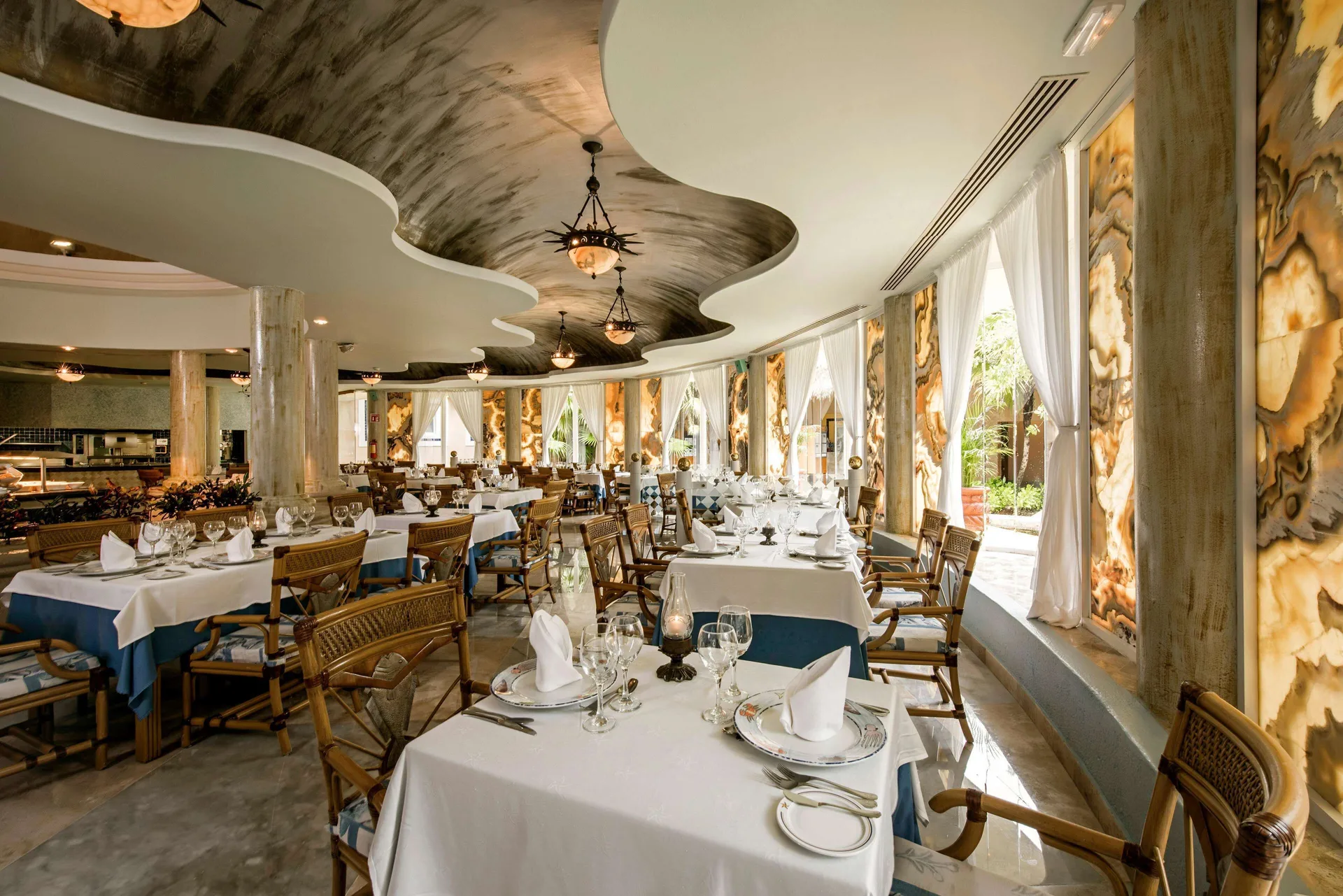 Elegant dining room with white tablecloths and arched windows at Iberostar Waves Paraíso del Mar.