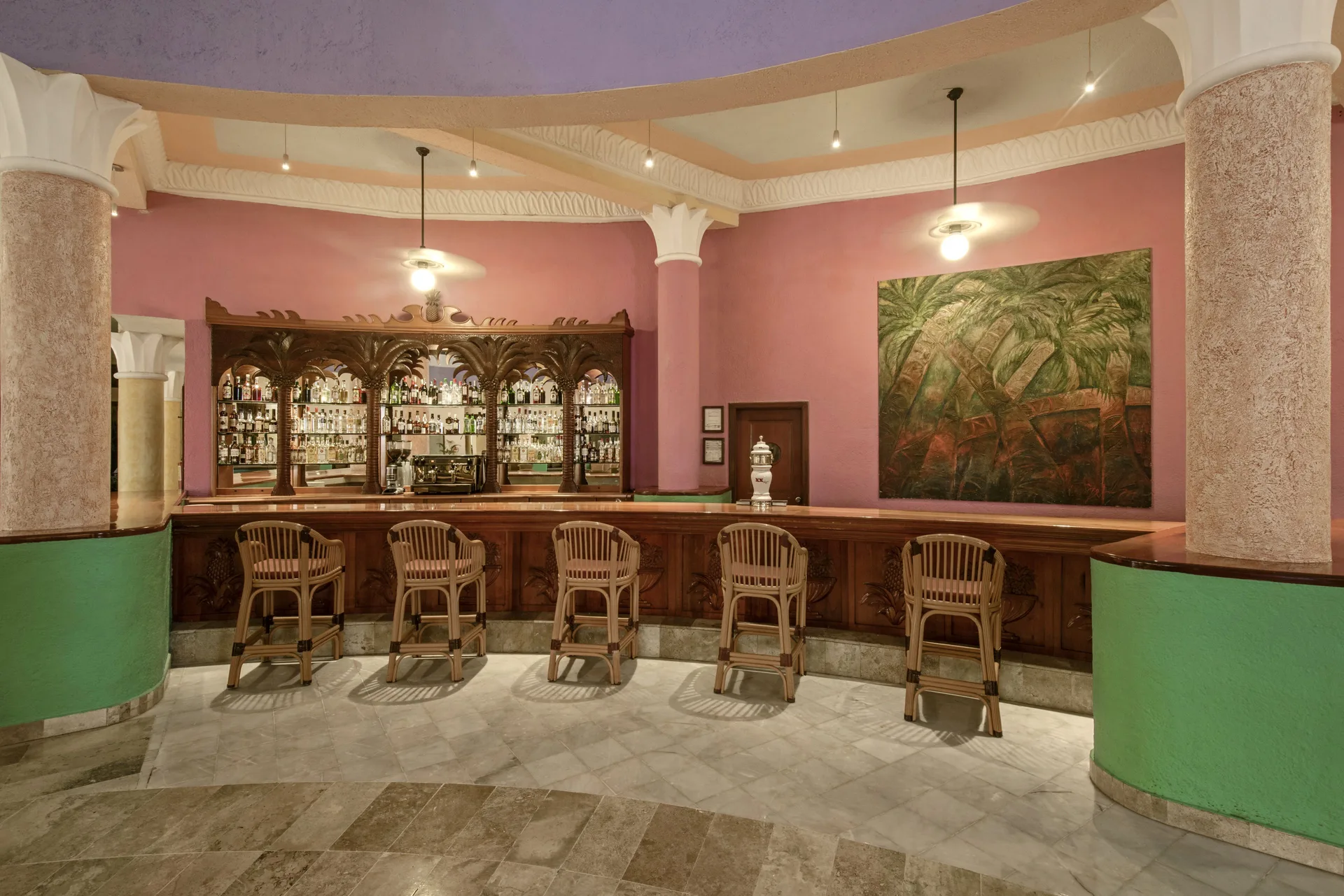 Lobby bar with carved wood counter and pink walls at Iberostar Waves Paraíso del Mar.