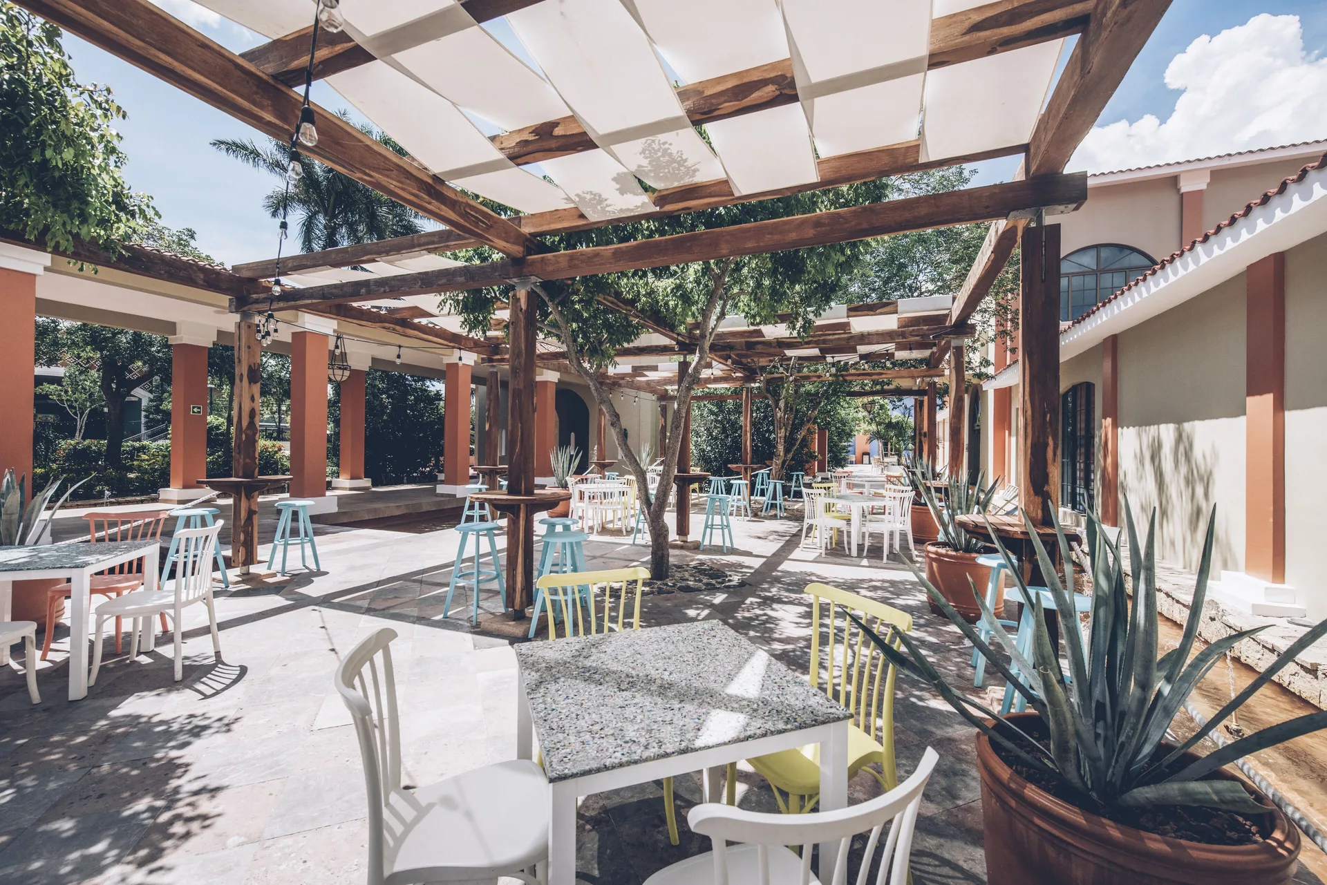 Outdoor patio with café tables and pergolas at Iberostar Waves Paraíso del Mar.