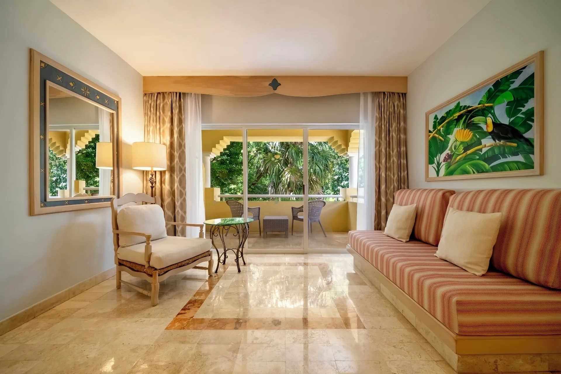 Junior Suite sitting area at Iberostar Waves Paraíso del Mar with striped sofa and balcony doors.