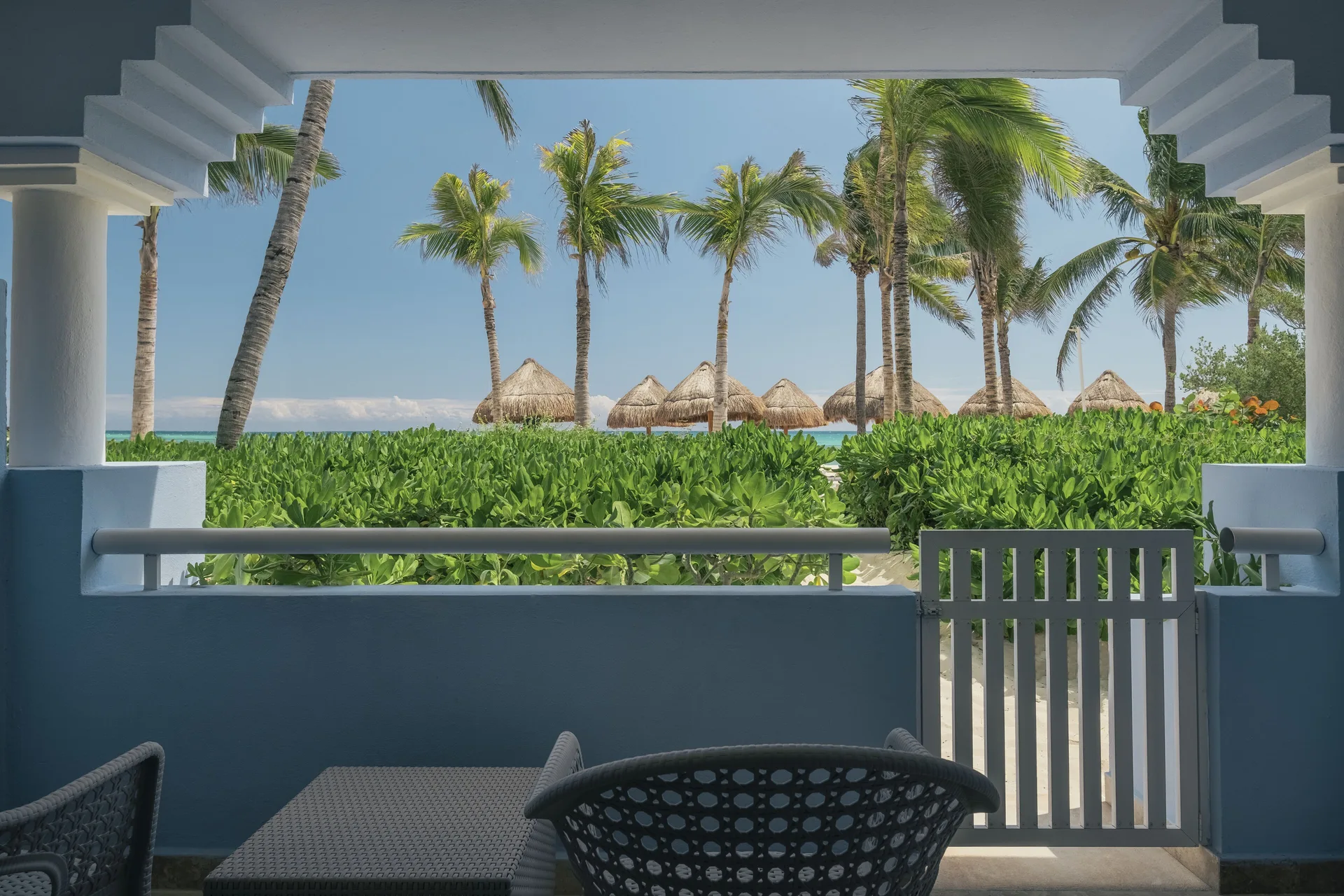 Beach access terrace with chairs and palm view at Iberostar Waves Paraíso del Mar.
