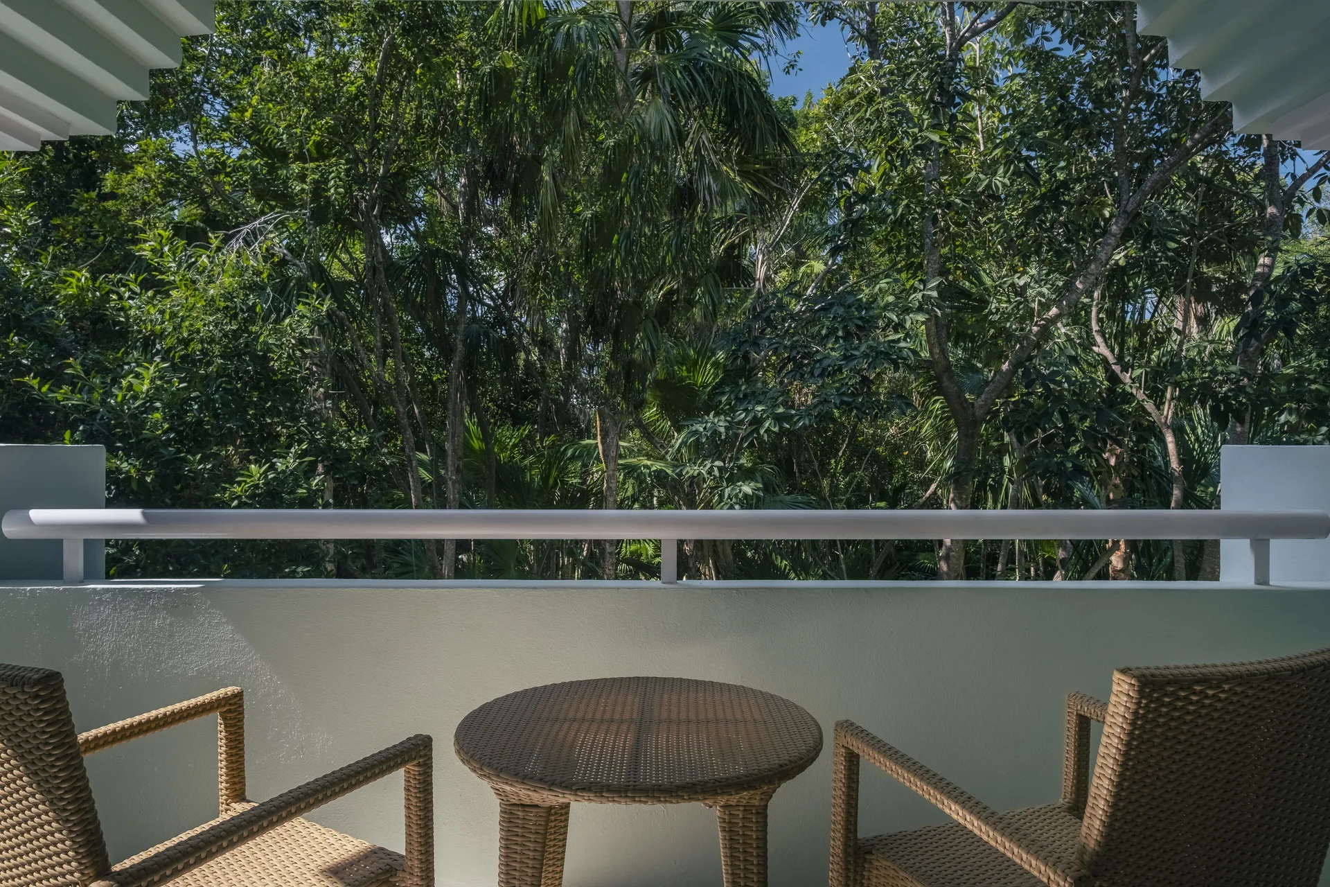 Premium Room balcony with wicker chairs and jungle view at Iberostar Waves Paraíso del Mar.