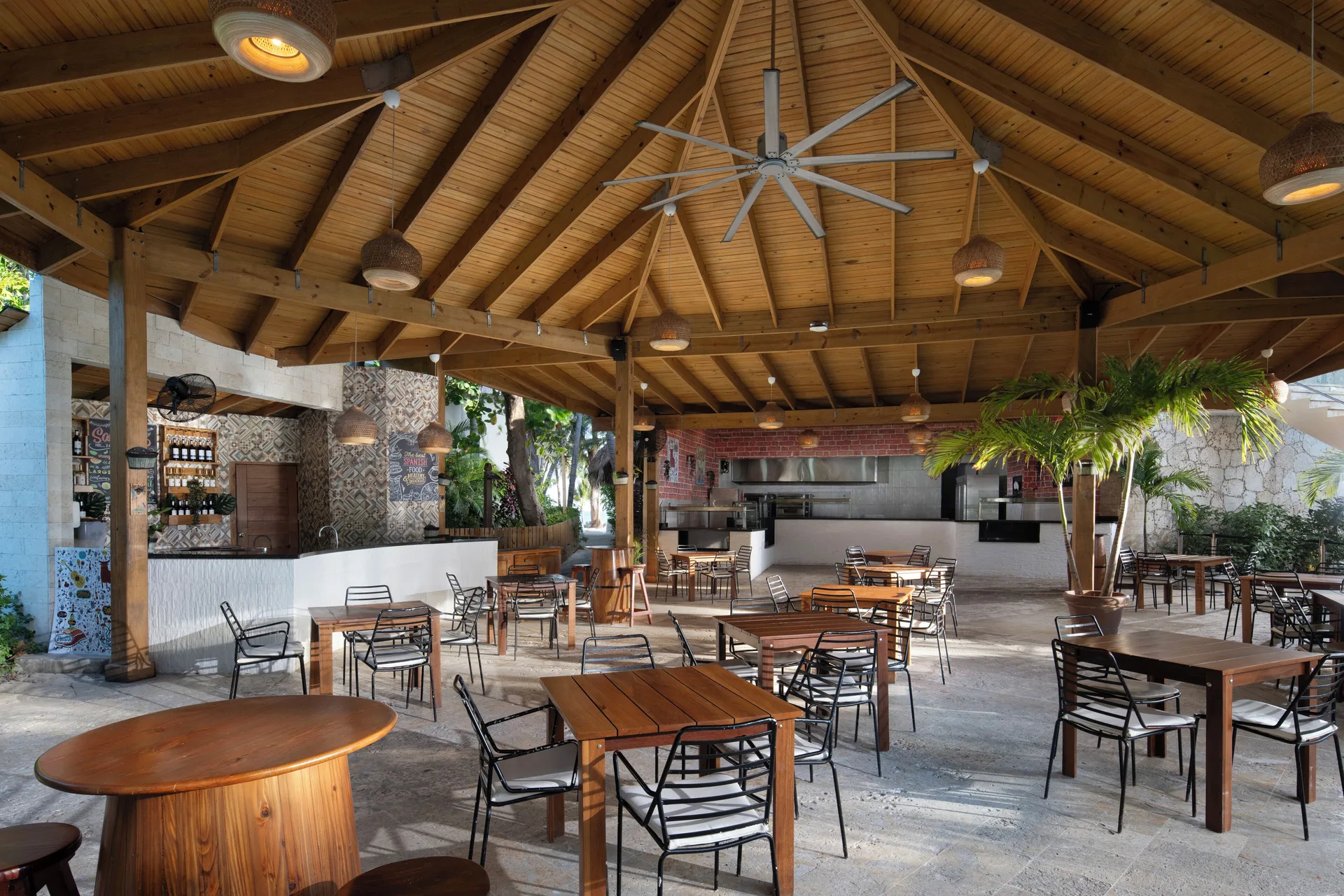 Casual covered grill dining area with wood tables at Impressive Premium Punta Cana.