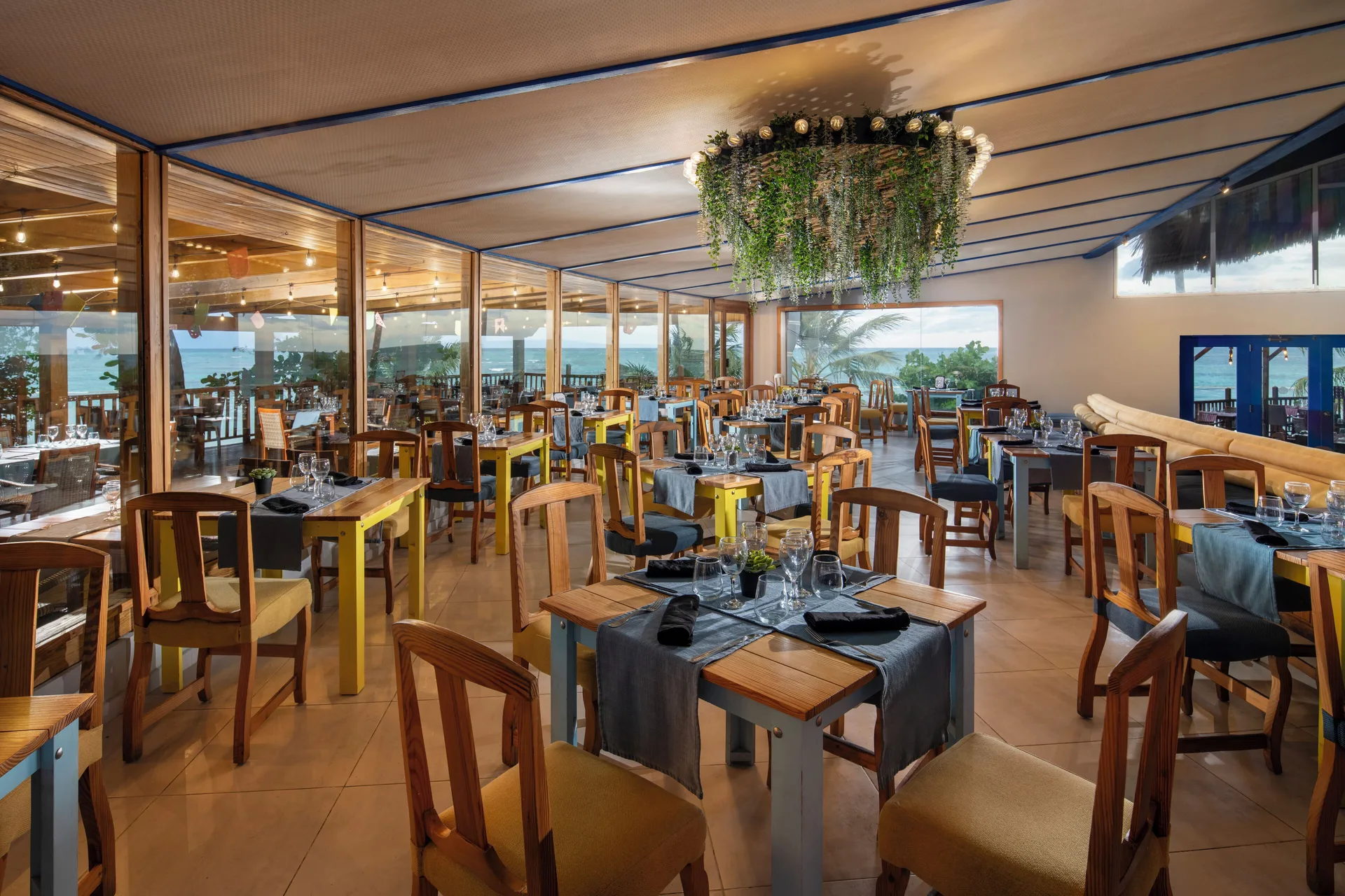 Indoor dining room with wood chairs and ocean-facing windows at Impressive Premium Punta Cana.