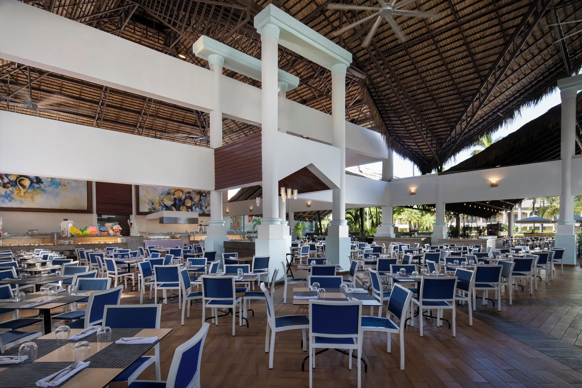 Large open-air dining room with blue chairs at Impressive Premium Punta Cana.