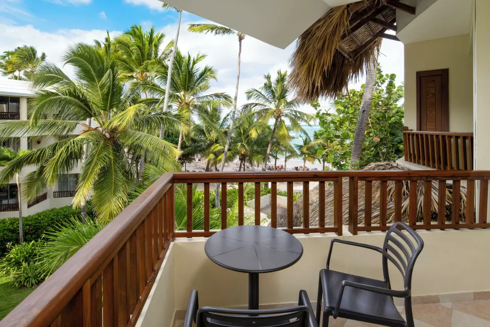 Balcony with table, chairs, palm trees, and ocean view at Impressive Premium Punta Cana.