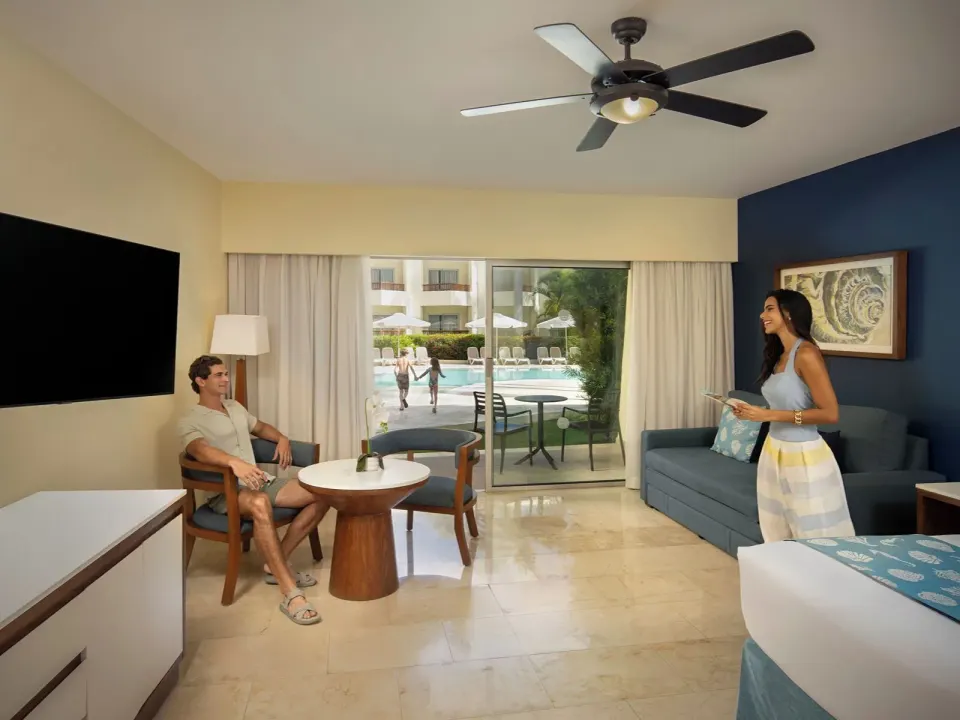 Junior Suite Premium Pool View room with sofa, bed, TV, balcony, and pool at Impressive Premium Punta Cana.