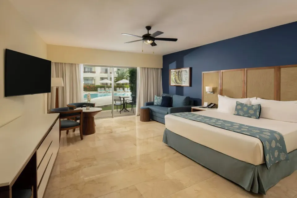 Junior Suite Premium Pool View king bed and patio doors at Impressive Premium Punta Cana.