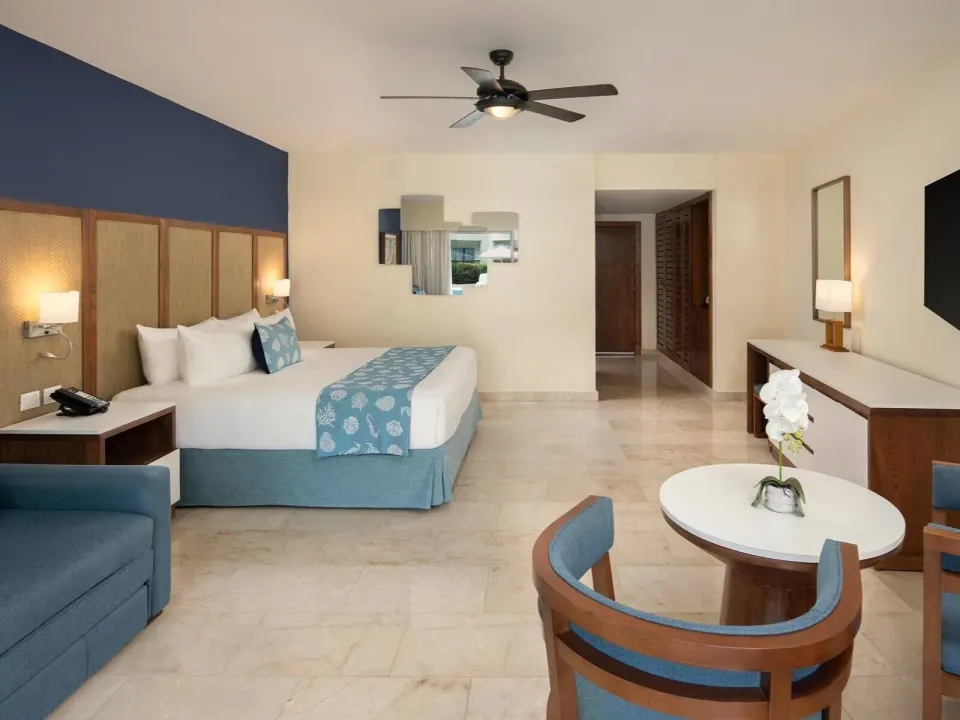 Junior Suite Premium Pool View king bed and sitting area at Impressive Premium Punta Cana.