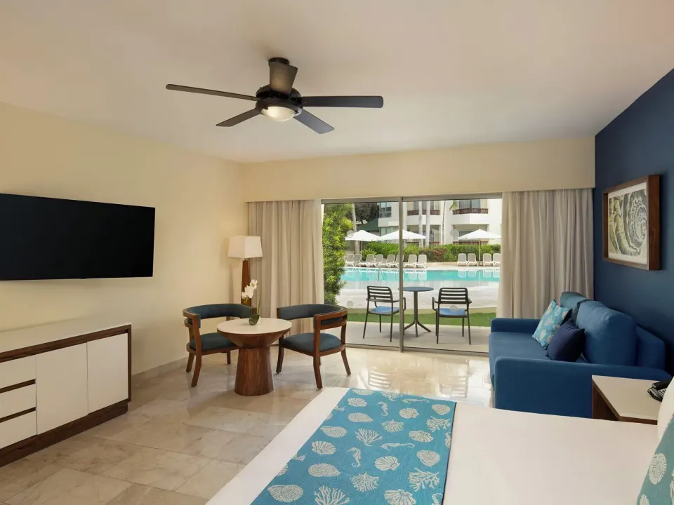 Junior Suite Premium Pool View king bed, sofa, and pool patio at Impressive Premium Punta Cana.
