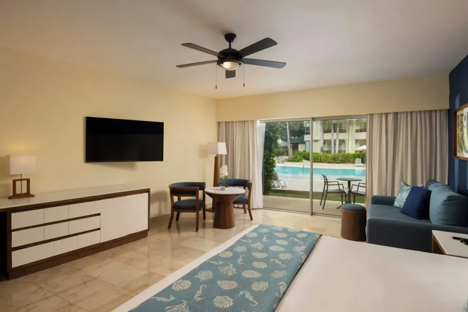 Junior Suite Premium Pool View room with TV, sofa, and patio at Impressive Premium Punta Cana.