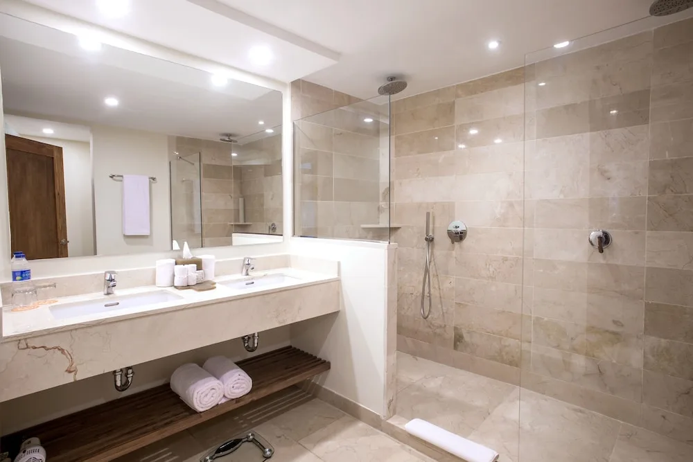 Bathroom with double sinks and glass shower in a suite at Impressive Premium Punta Cana.