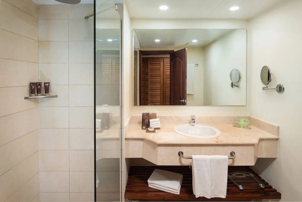 Suite bathroom vanity and glass shower with bath amenities at Impressive Premium Punta Cana.