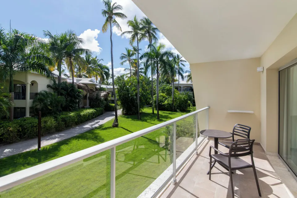 Junior Suite Premium Tropical View balcony with chairs and garden view at Impressive Premium Punta Cana.