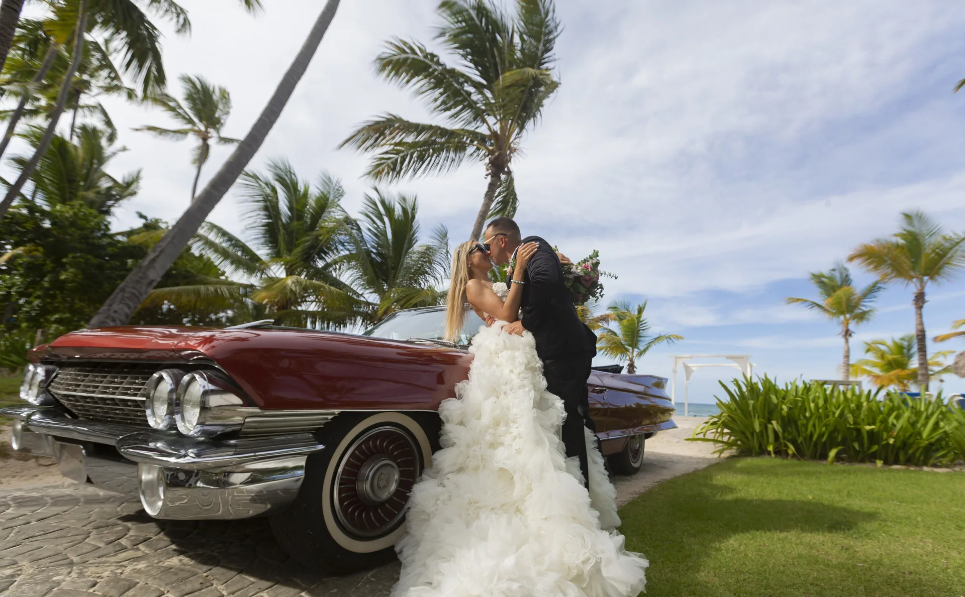 Wedding couple beside a red vintage convertible at Impressive Premium Punta Cana.
